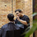 Barber cutting hair with clippers in a salon.