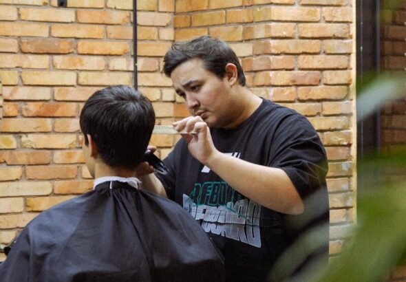 Barber cutting hair with clippers in a salon.